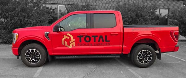 A red Total Tools and Supplies pickup truck in front of our shop.
